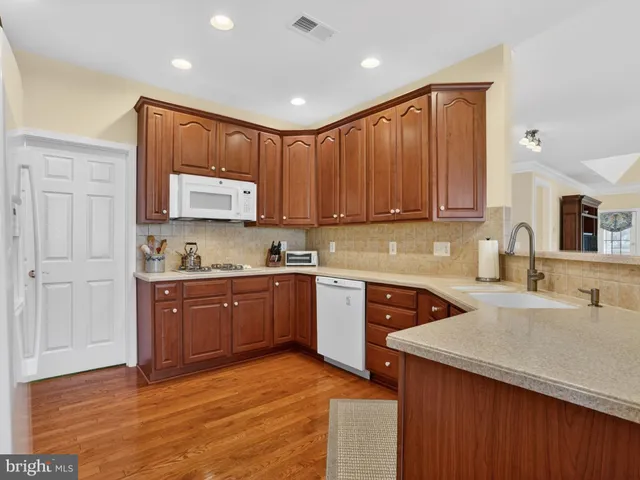 a kitchen with stainless steel appliances granite countertop a sink dishwasher stove and cabinets with wooden floor