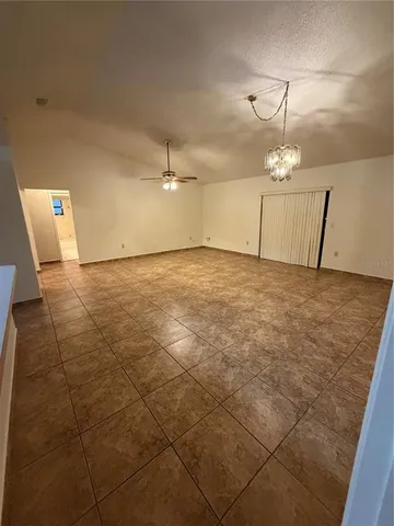 a view of an empty room and chandelier fan