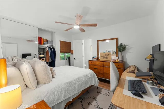 a bedroom with bed a flat tv screen and a desk