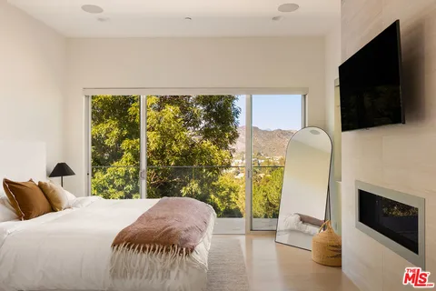 a bedroom with a bed a flat screen tv and a fireplace