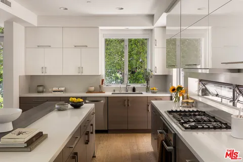 a kitchen with a sink a stove a window cabinetry and a kitchen island