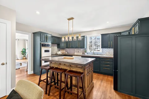 a kitchen with granite countertop a stove a refrigerator and wooden floor