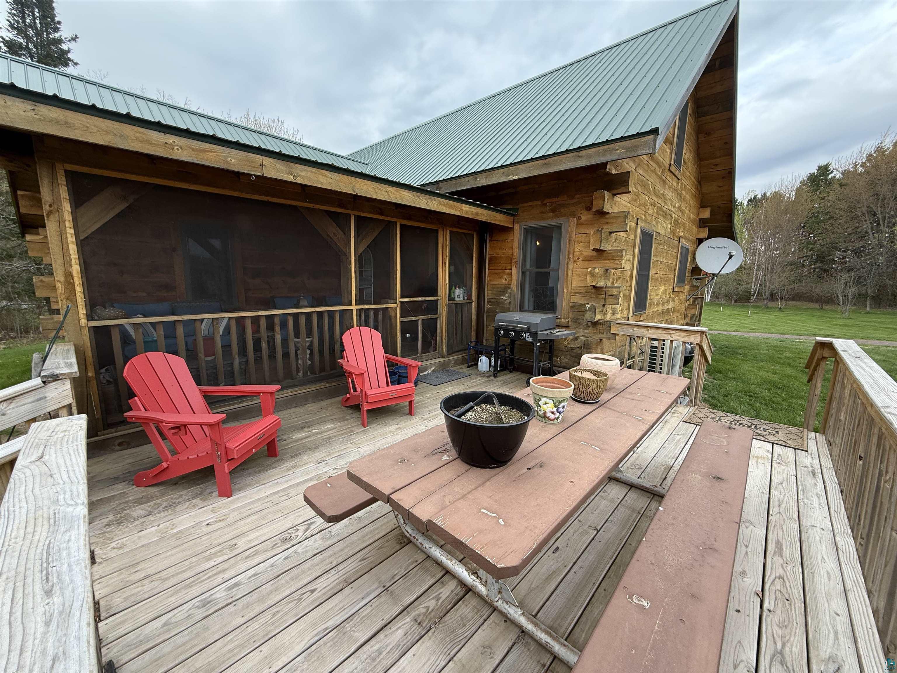 37590 Degerstrom Road Askov, MN 55704 - Photo 34 of 53 Expansive exterior wood-finish deck with a screened porch featuring a log cabin structure and a green metal roof