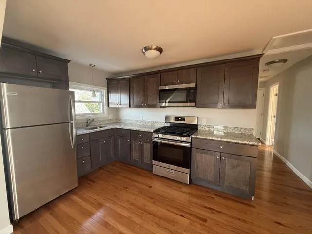 a kitchen with granite countertop a refrigerator stove and sink