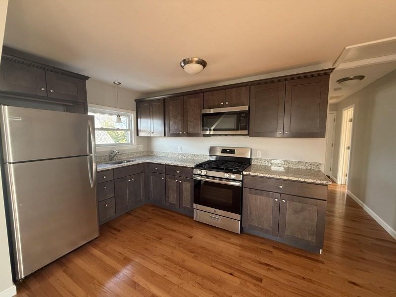 a kitchen with granite countertop a refrigerator stove and sink