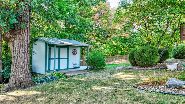 a view of a house with a small yard plants and large tree