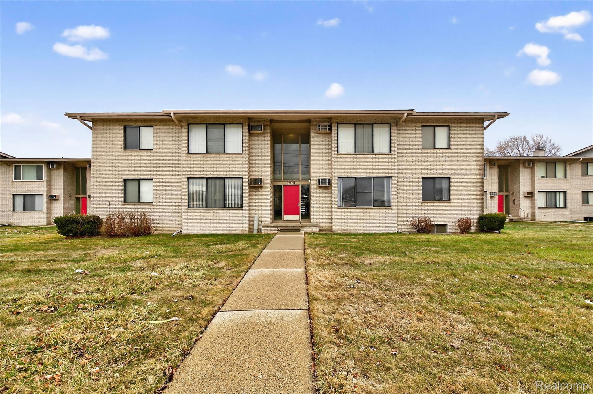 32650 Mound Road, Unit 4 Warren, MI 48092 - Photo 1 of 32 Brick exterior with multiple windows, prominent red entry doors, and a central walkway