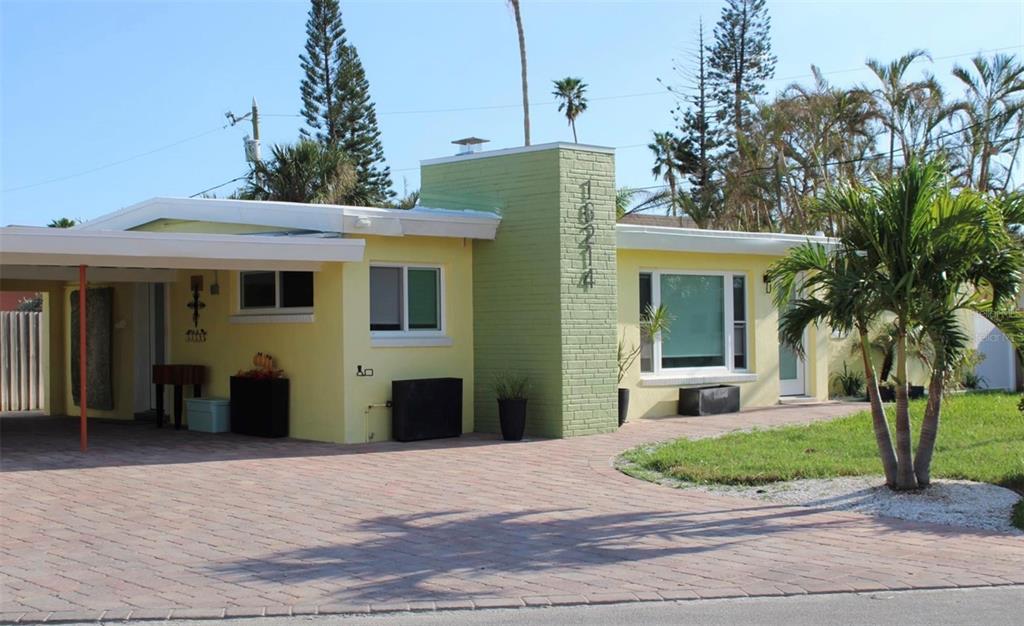 a view of a white house with a small yard and potted plants