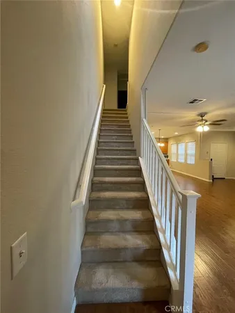 a view of staircase with lots of frames on wall and wooden floor