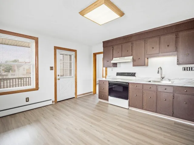 a kitchen with granite countertop a stove a sink and a refrigerator