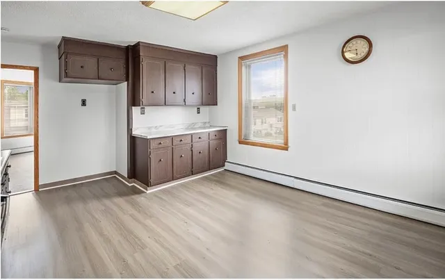 a view of an empty room with window and wooden floor