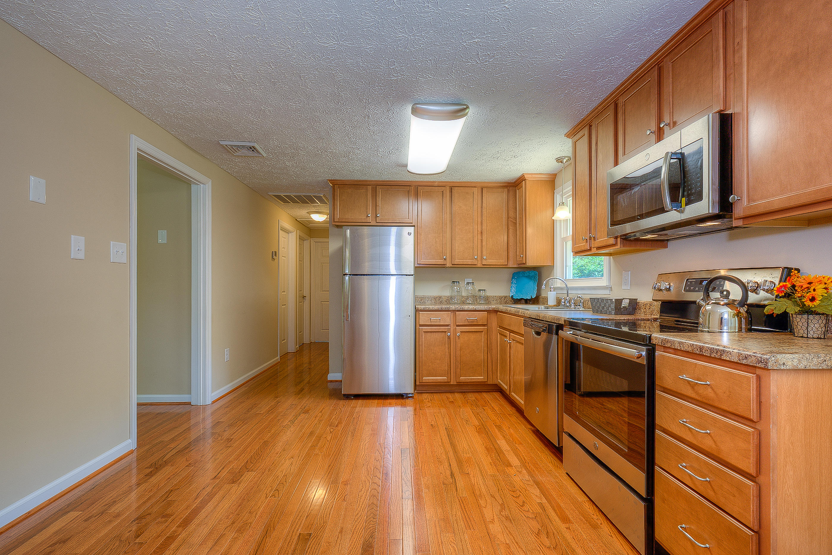 2509 Rutrough Road Southeast Roanoke, VA 24014 - Photo 11 of 28 a kitchen with stainless steel appliances granite countertop a refrigerator a stove top oven a sink and dishwasher with wooden floor