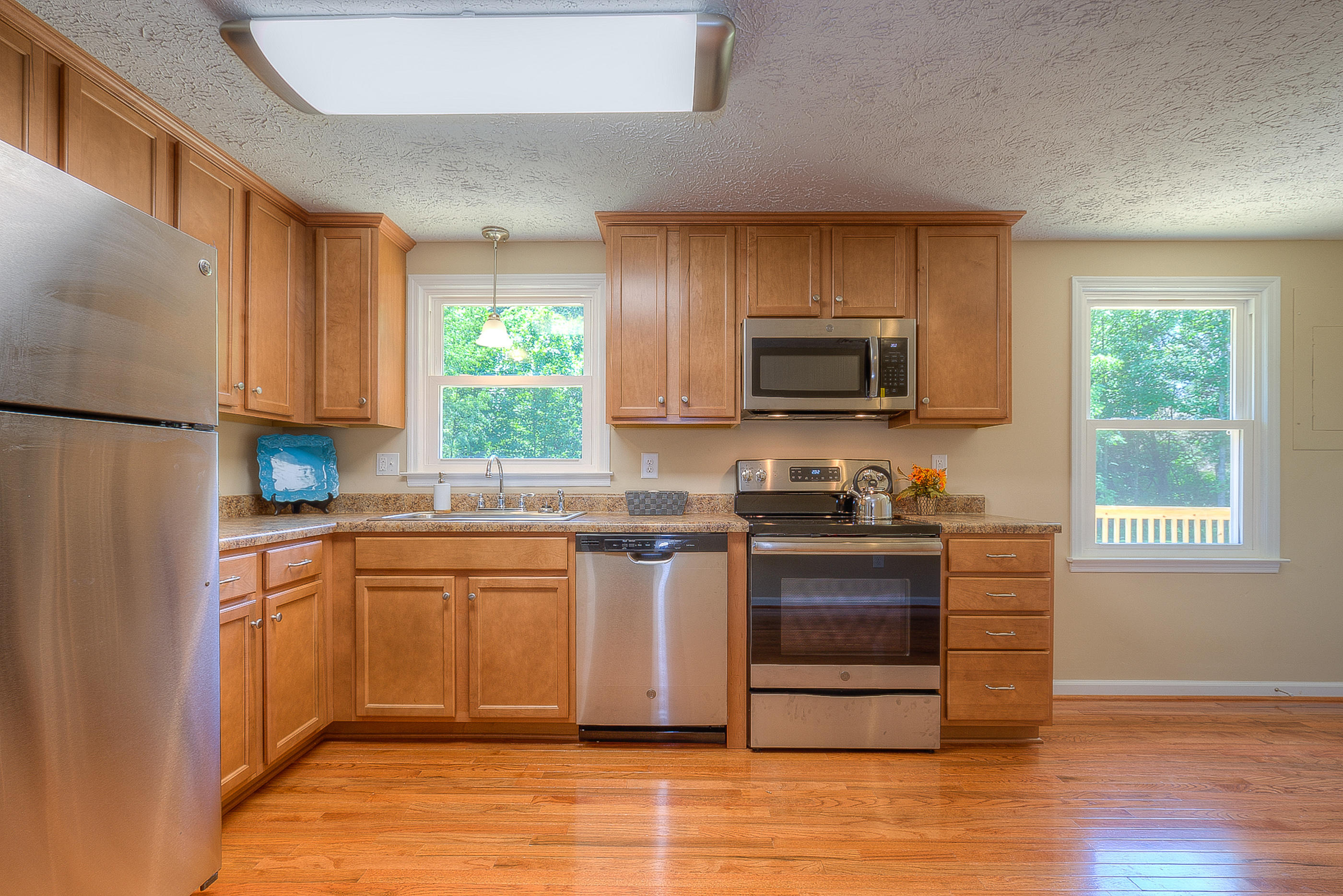 2509 Rutrough Road Southeast Roanoke, VA 24014 - Photo 9 of 28 a kitchen with stainless steel appliances granite countertop a stove a sink dishwasher and a microwave oven with wooden floor