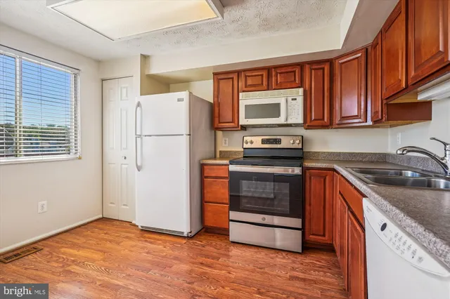 a kitchen with granite countertop wooden cabinets a sink and dishwasher