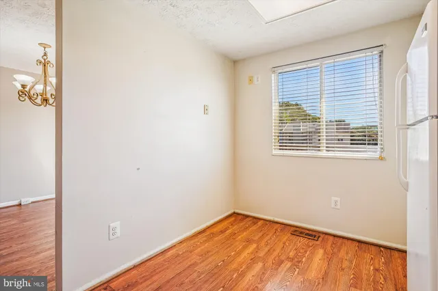 a view of an empty room with wooden floor stairs and a window