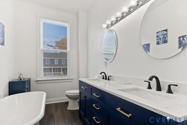 a bathroom with a double vanity sink a mirror a toilet and a window