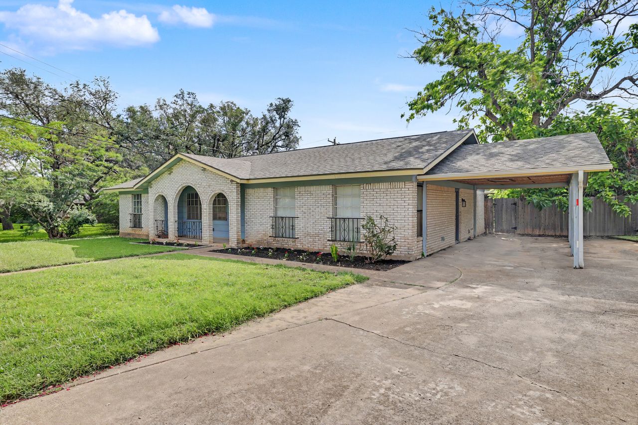 1811 Terry Lane Georgetown, TX 78628 - Photo 2 of 40 A charming single-story brick home features a spacious driveway leading to a convenient carport.