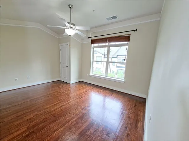 an empty room with wooden floor chandelier fan and windows