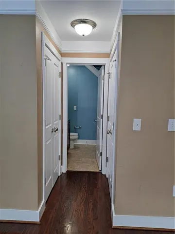 a view of a hallway with wooden floor and a bathroom