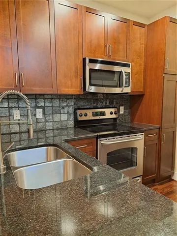 a kitchen with stainless steel appliances wooden cabinets a sink and a microwave