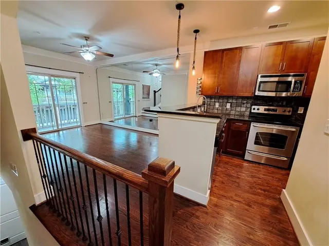 a kitchen with stainless steel appliances granite countertop a stove top oven a sink dishwasher a dining table and chairs with wooden floor