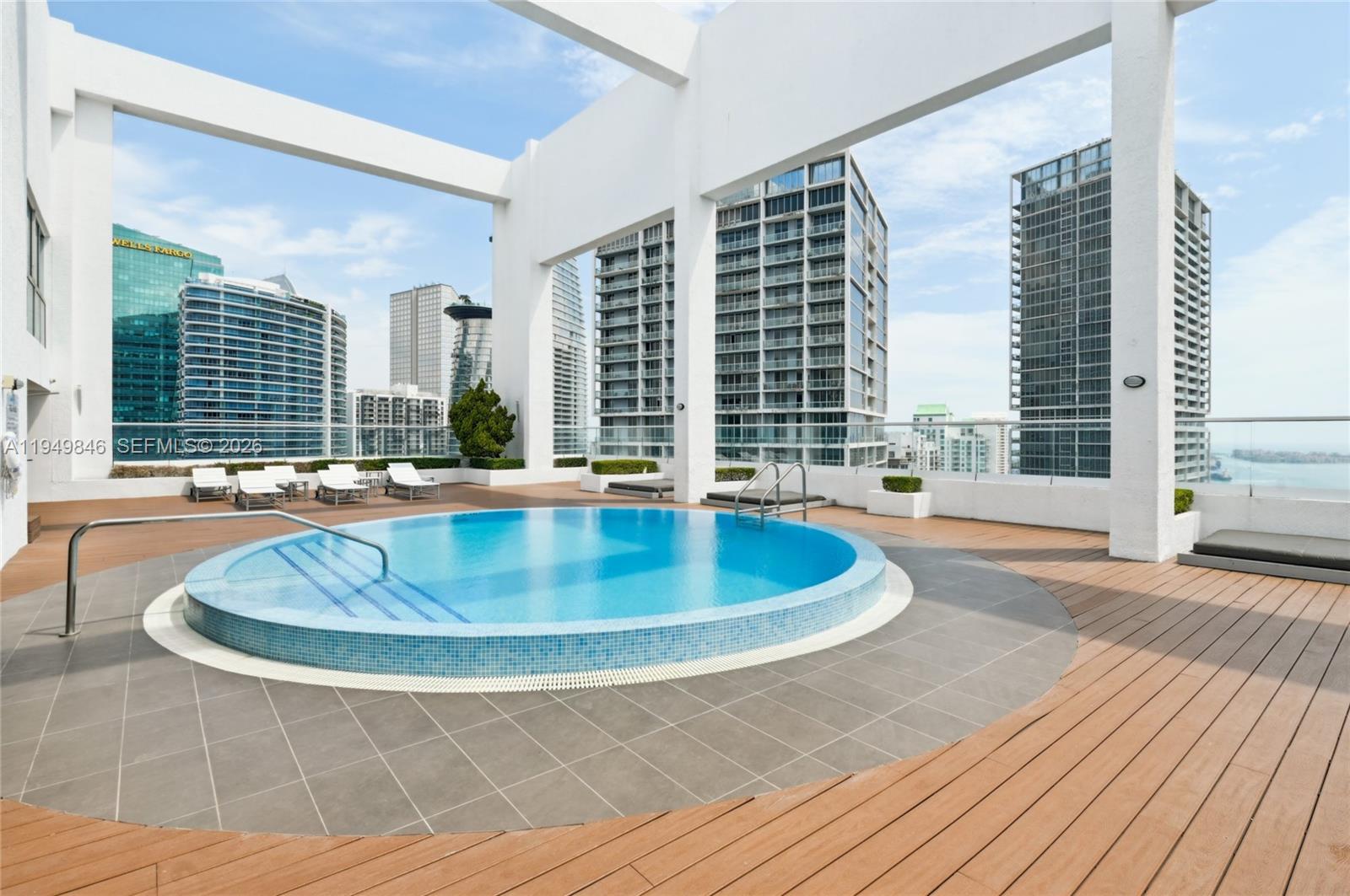 55 Southeast 6th Street, Unit 1608 Miami, FL 33131 - Photo 17 of 24 Infinity-edge pool surrounded by modern lounge chairs and Miami’s cityscape backdrop.
