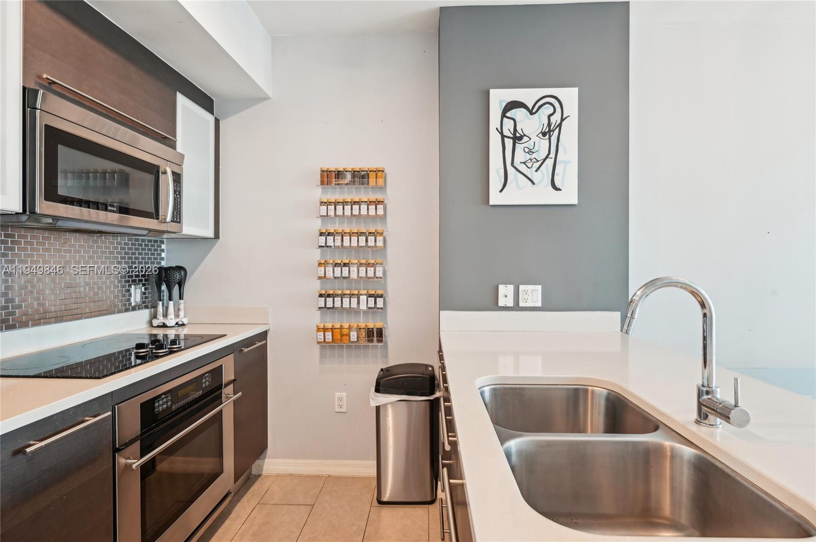 55 Southeast 6th Street, Unit 1608 Miami, FL 33131 - Photo 7 of 24 Spacious kitchen with modern lighting and custom wood finishes, ideal for Miami lifestyle cooking and hosting.