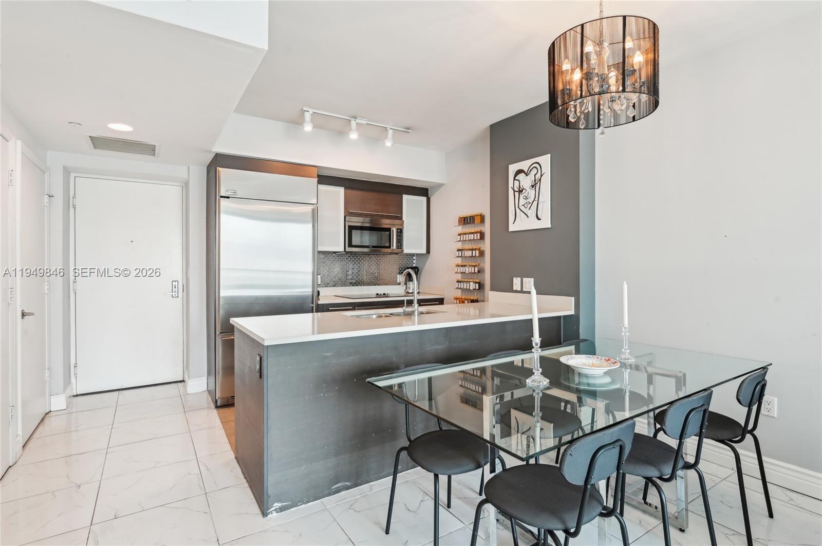 55 Southeast 6th Street, Unit 1608 Miami, FL 33131 - Photo 8 of 24 Stylish dining area adjacent to open kitchen, blending comfort and elegance in a high-rise Miami residence.