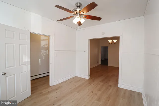 an empty room with wooden floor and a ceiling fan