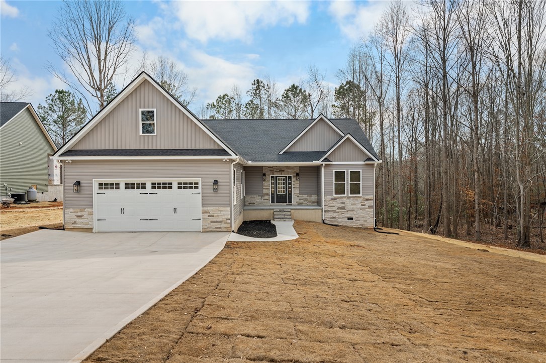 This modern home features a welcoming entrance, attached garage, and charming stone accents.