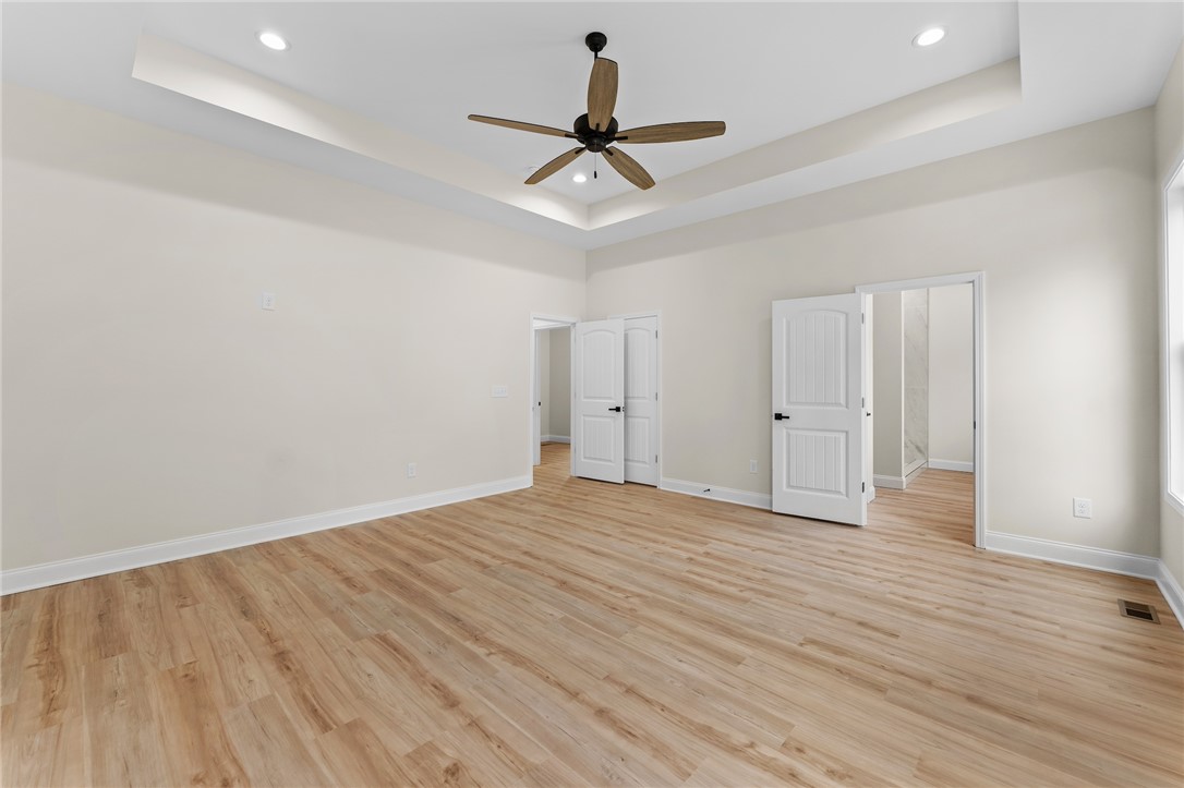 333 Lone Oak Road Anderson, SC 29621 - Photo 21 of 36 This spacious primary bedroom features hardwood flooring and a tray ceiling, offering a comfortable retreat.