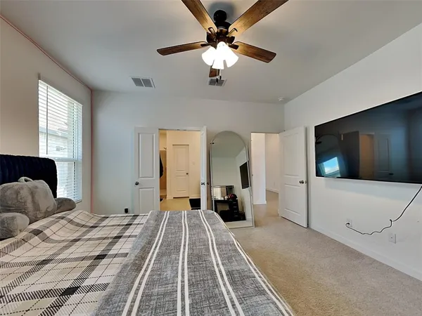 a bedroom with a large bed and a flat tv screen on dresser
