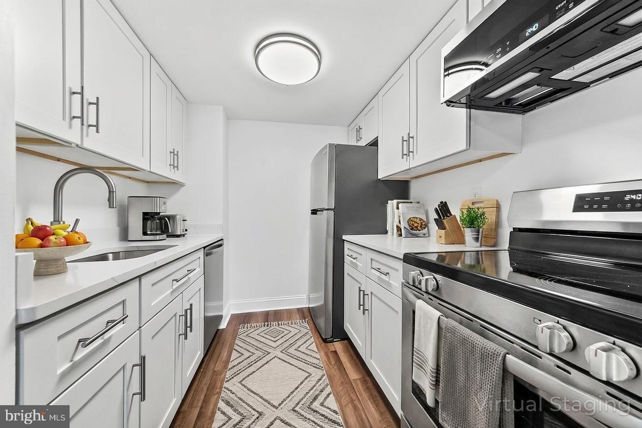a kitchen with stainless steel appliances granite countertop a sink stove refrigerator and cabinets