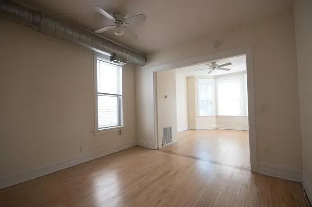 an empty room with wooden floor and windows