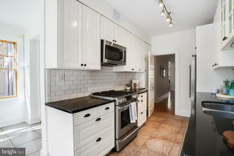 a kitchen with stainless steel appliances granite countertop white cabinets a stove top oven a sink and dishwasher