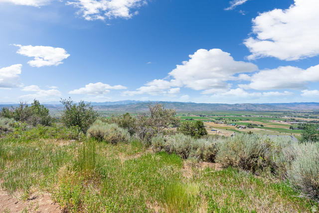 2459 Painter Road Marion, UT 84036 - Photo 15 of 42 Expansive rural landscape featuring distant mountains, agricultural fields, and scattered structures under a broad sky with white clouds