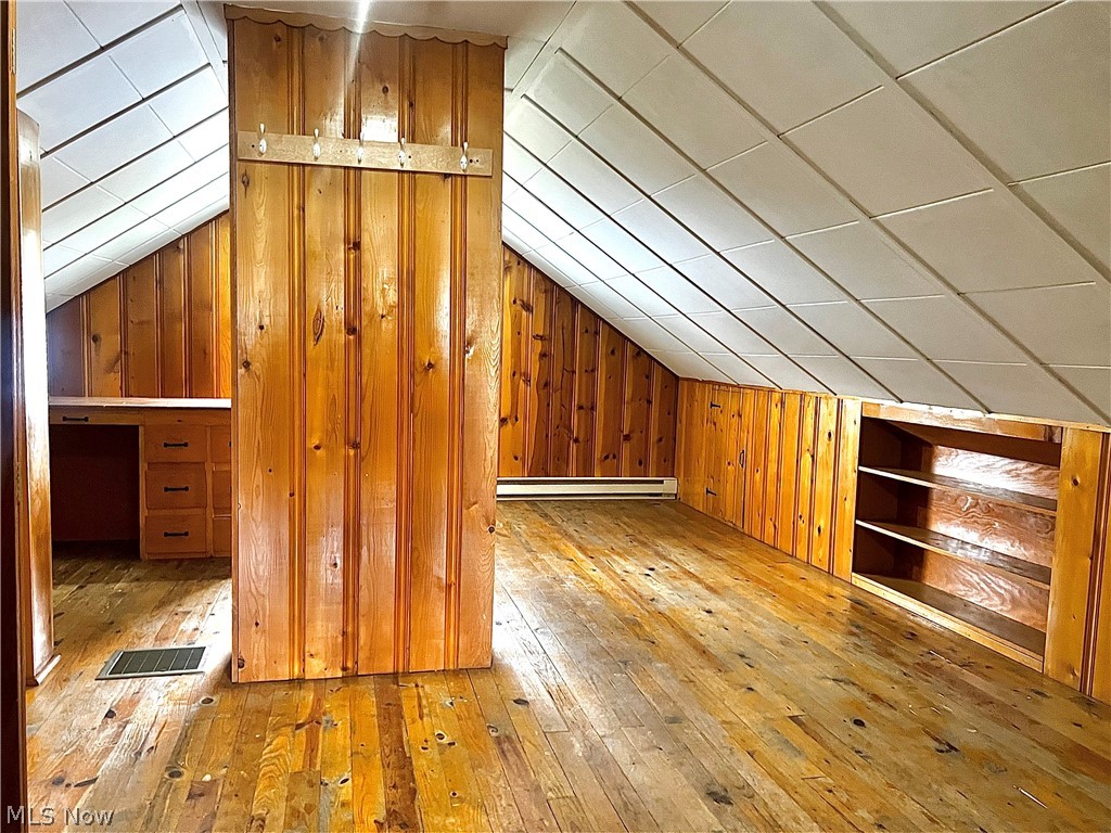 67 Forbes Road Bedford, OH 44146 - Photo 14 of 20 Additional living space featuring light wood-style flooring, wooden walls, lofted ceiling, built in features, and a baseboard radiator