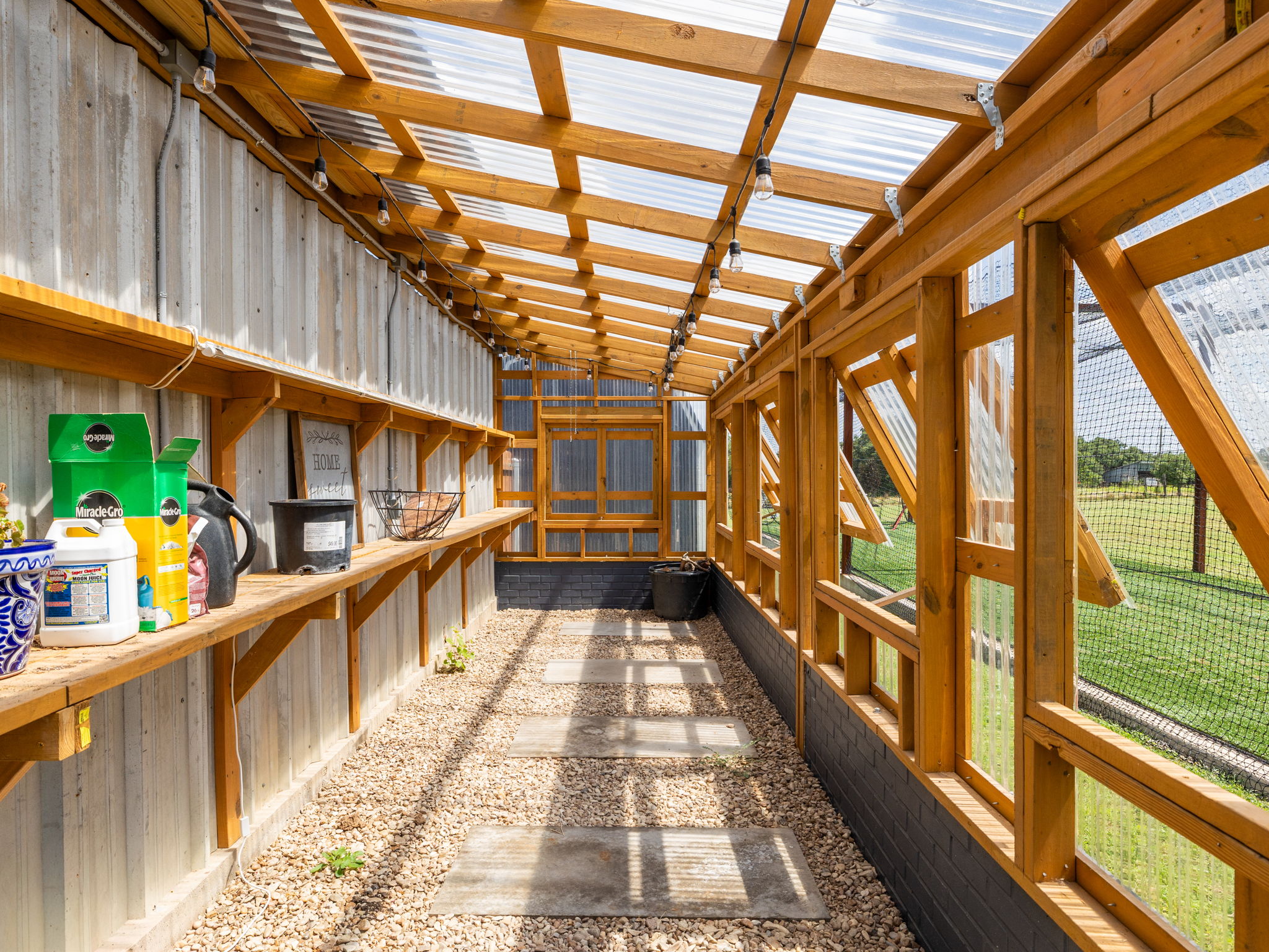 3001 County Road 255 Georgetown, TX 78633 - Photo 7 of 35 A sun-drenched greenhouse provides a tranquil space for cultivating plants, featuring sturdy wooden framing and clear paneling.