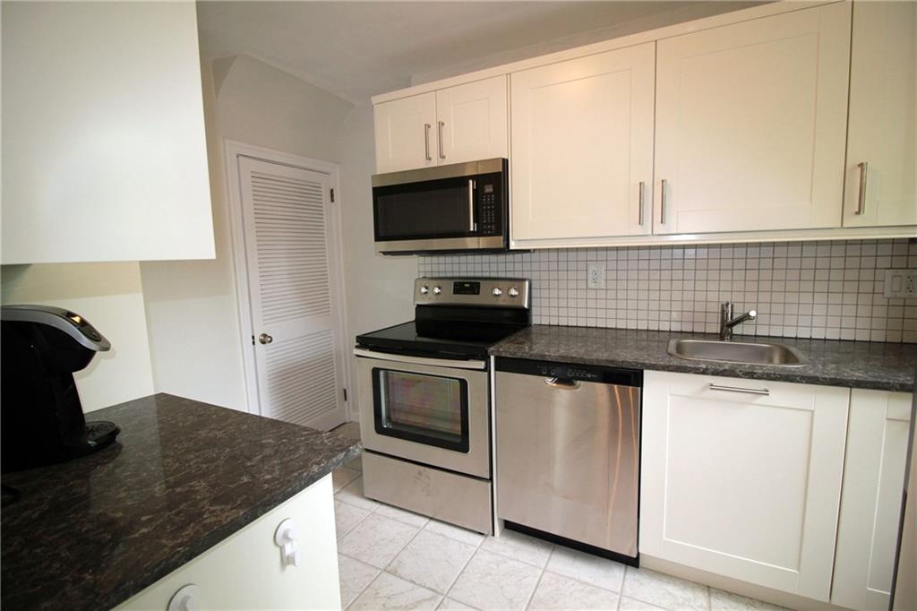 406 Olympia Road Pittsburgh, PA 15211 - Photo 8 of 13 The newly updated kitchen features ample cabinet space, solid stone counters, stainless appliances, and tile backsplash and floor. Access to the walk-out basement is through the door in the corner.