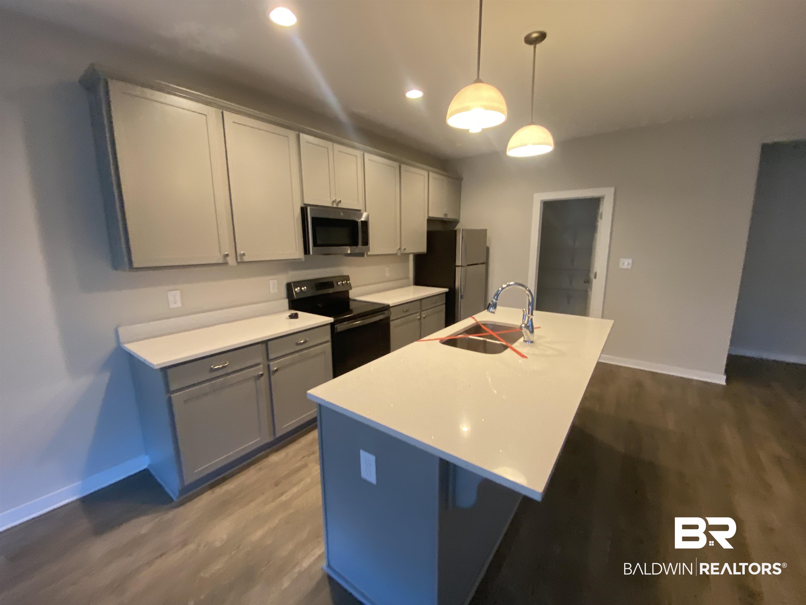 1279 Cater Lee Way Foley, AL 36535 - Photo 10 of 12 Kitchen with sink, gray cabinets, an island with sink, decorative light fixtures, and stainless steel appliances