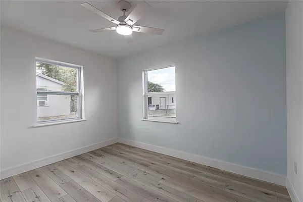a view of empty room with wooden floor and fan