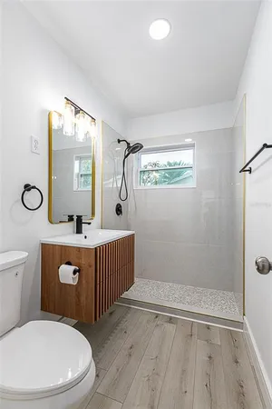 a bathroom with a toilet a sink a mirror a vanity and window