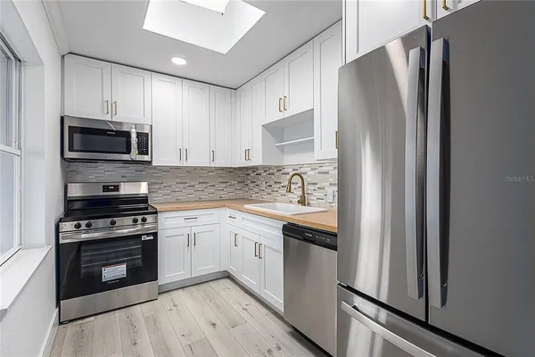 a kitchen with stainless steel appliances a refrigerator sink and microwave