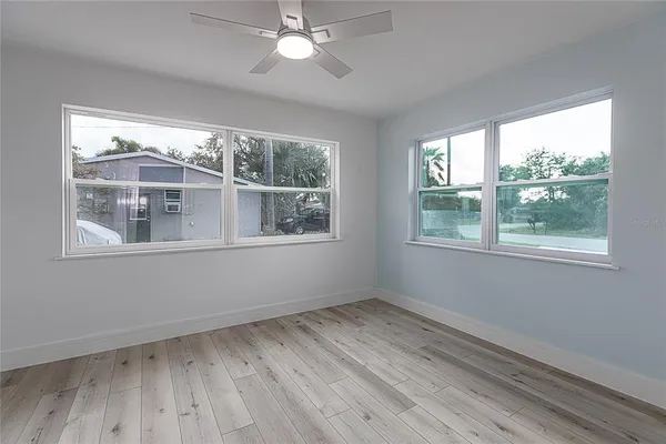 a view of empty room with wooden floor and fan