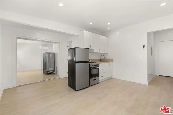 a view of kitchen with refrigerator cabinets and wooden floor