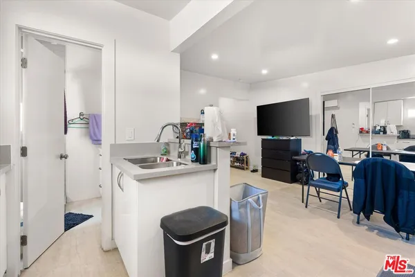 a living room with stainless steel appliances furniture a fireplace and a flat screen tv
