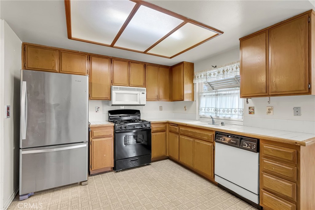 2892 Jackson Street Riverside, CA 92503 - Photo 9 of 29 a kitchen with stainless steel appliances granite countertop a refrigerator a sink dishwasher a stove with wooden cabinets