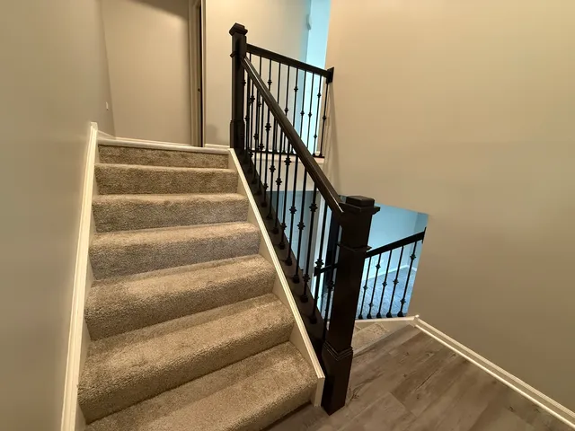 a view of staircase with railing and white walls