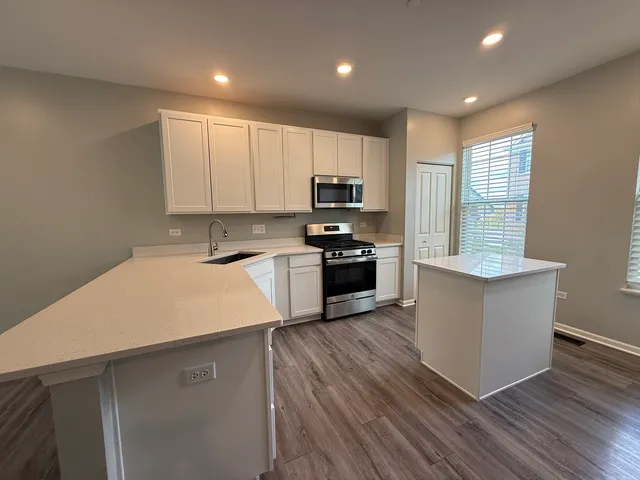 a kitchen with wooden floors and white stainless steel appliances