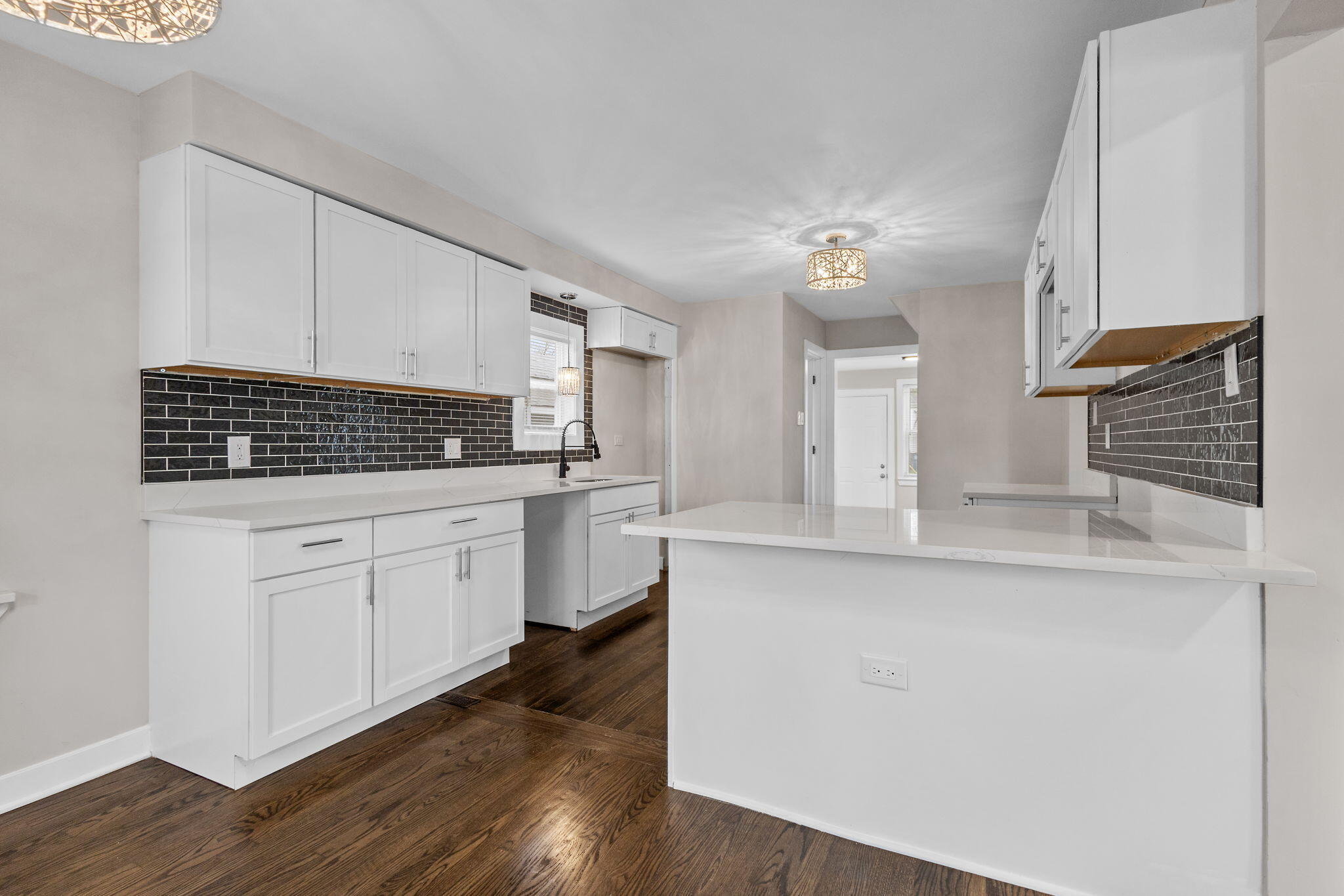 4680 Harrison Street Gary, IN 46408 - Photo 8 of 26 a kitchen with white cabinets a sink dishwasher and a stove with wooden floor